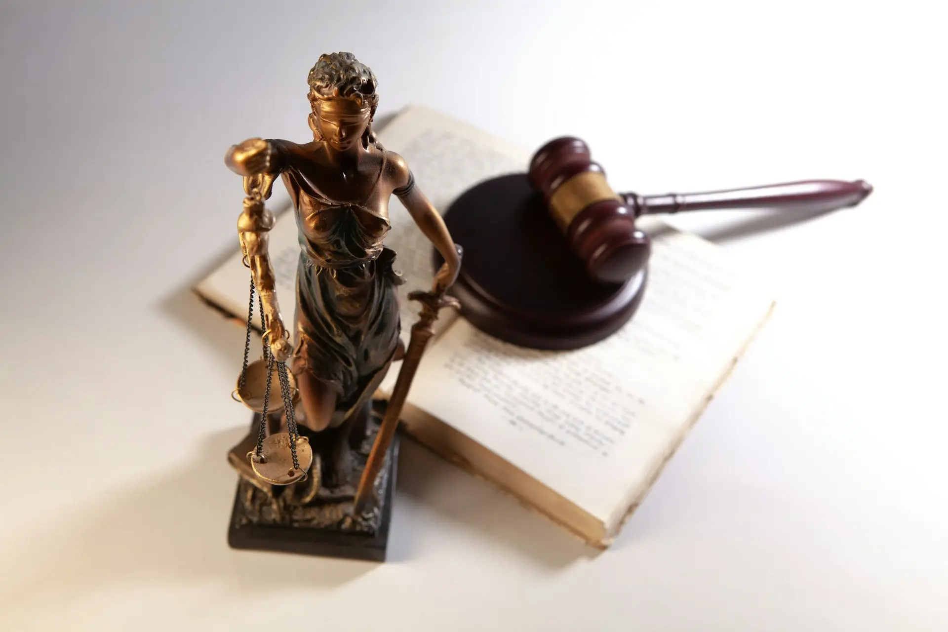 Statue of justice, gavel, and open book on table